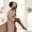 Woman with deep brown skin examining her leg in a bathroom