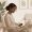 Woman with deep brown skin sitting in a clinical waiting room with a notebook