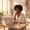Woman with deep brown skin working at a desk near a window
