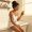 Woman with light-brown skin sitting on a bathtub edge reconsidering her skincare approach