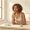 Woman with medium-brown skin calmly evaluating skincare products and white supplement capsules arranged on her bathroom counter