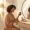 Woman with medium-deep skin tone calmly evaluating skincare products at her vanity