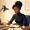 Woman with rich dark skin thoughtfully writing in a notebook at a desk in warm lamplight