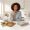 Woman with warm brown skin choosing between two different meals at a kitchen counter