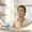 woman with olive-brown skin examining her cheek closely in a bathroom mirror