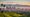 Golden winter light over Los Angeles skyline with green hills and snow-capped San Gabriel Mountains after a rainstorm.