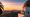 Griffith Observatory at sunset overlooking Los Angeles skyline, golden domes glowing above city lights and a pastel evening sky.