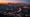 Los Angeles skyline at blue hour with freeway light trails and fading sunset glow.