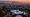 Sunset over Los Angeles skyline from the hills with palm silhouettes and mountains in distance.