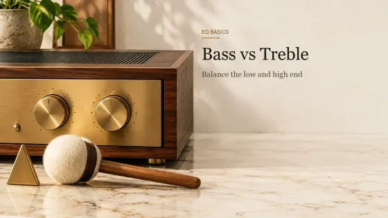 A walnut and brass stereo amplifier with two large tone knobs, a brass triangle and a felt bass-drum mallet on a marble counter.