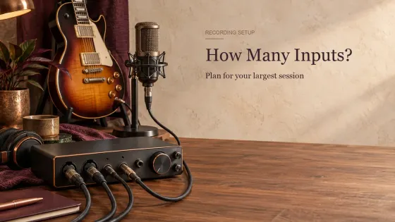 Desktop audio interface with several cables plugged in leading to a studio microphone and an electric guitar