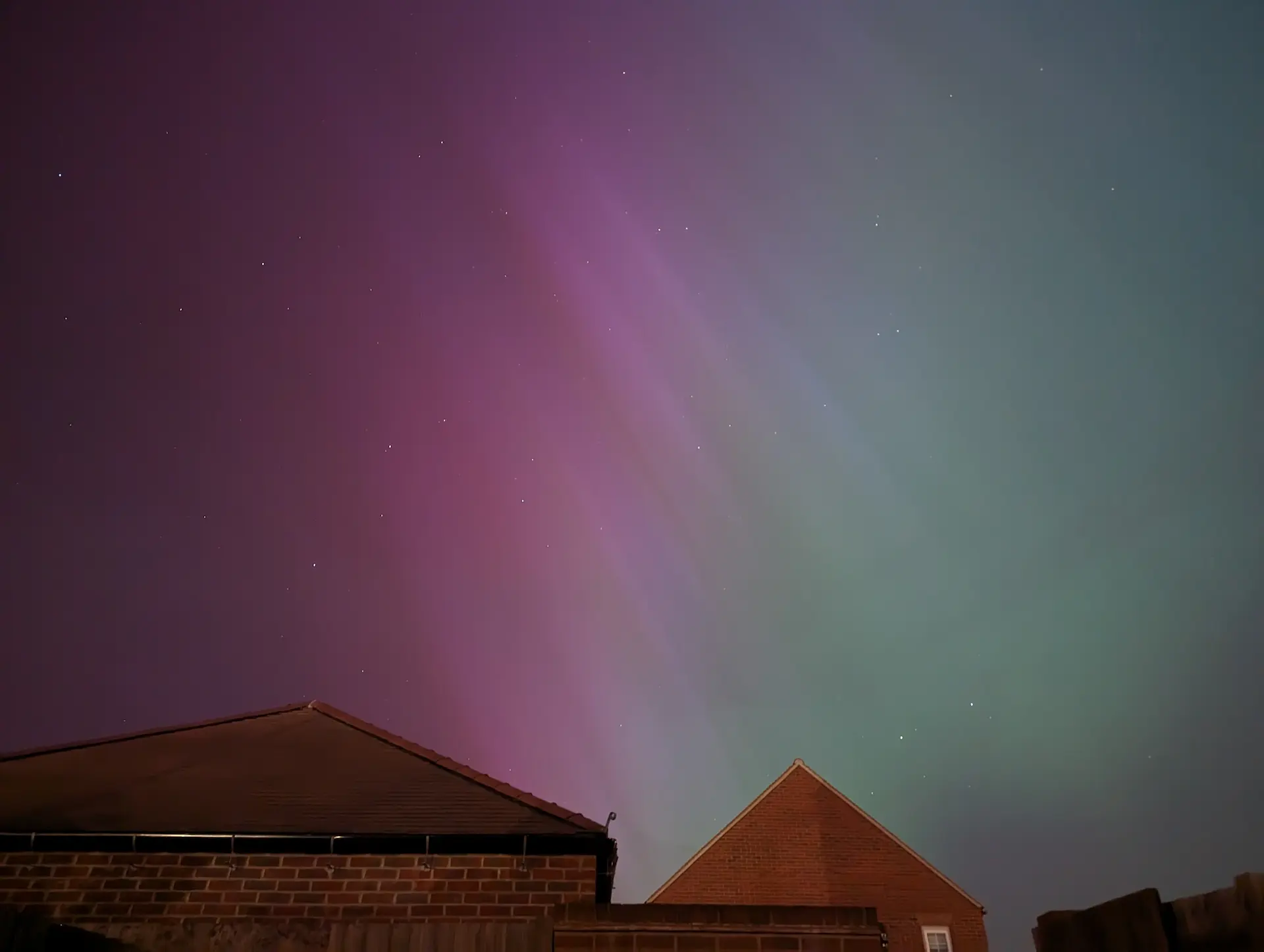 Garage and neighbour’s house with green and pink Northern Lights.