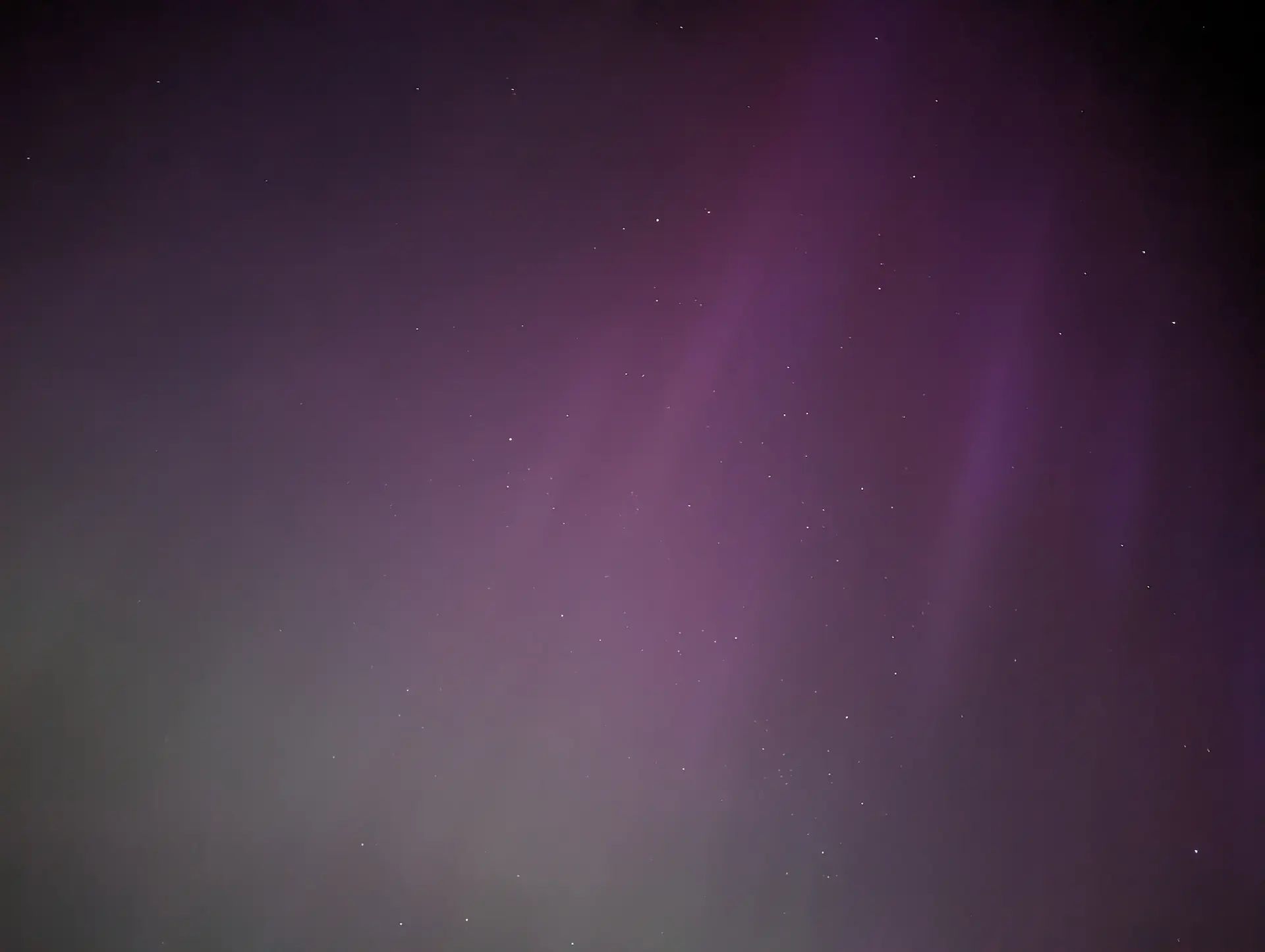 Faint green and purple Northern Light streaks in the night sky.