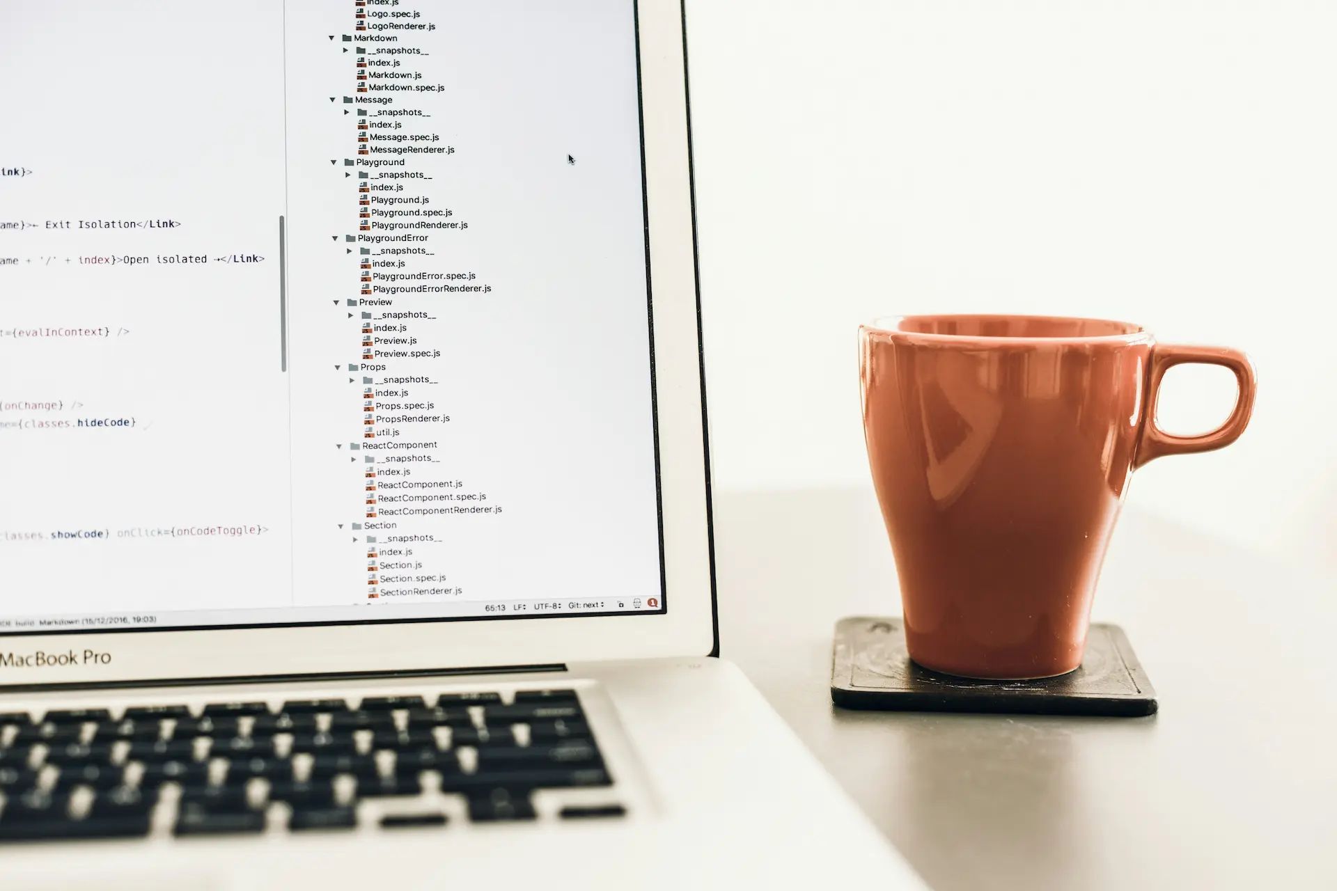 Image of a laptop with a code editor open and an orange mug next to it.