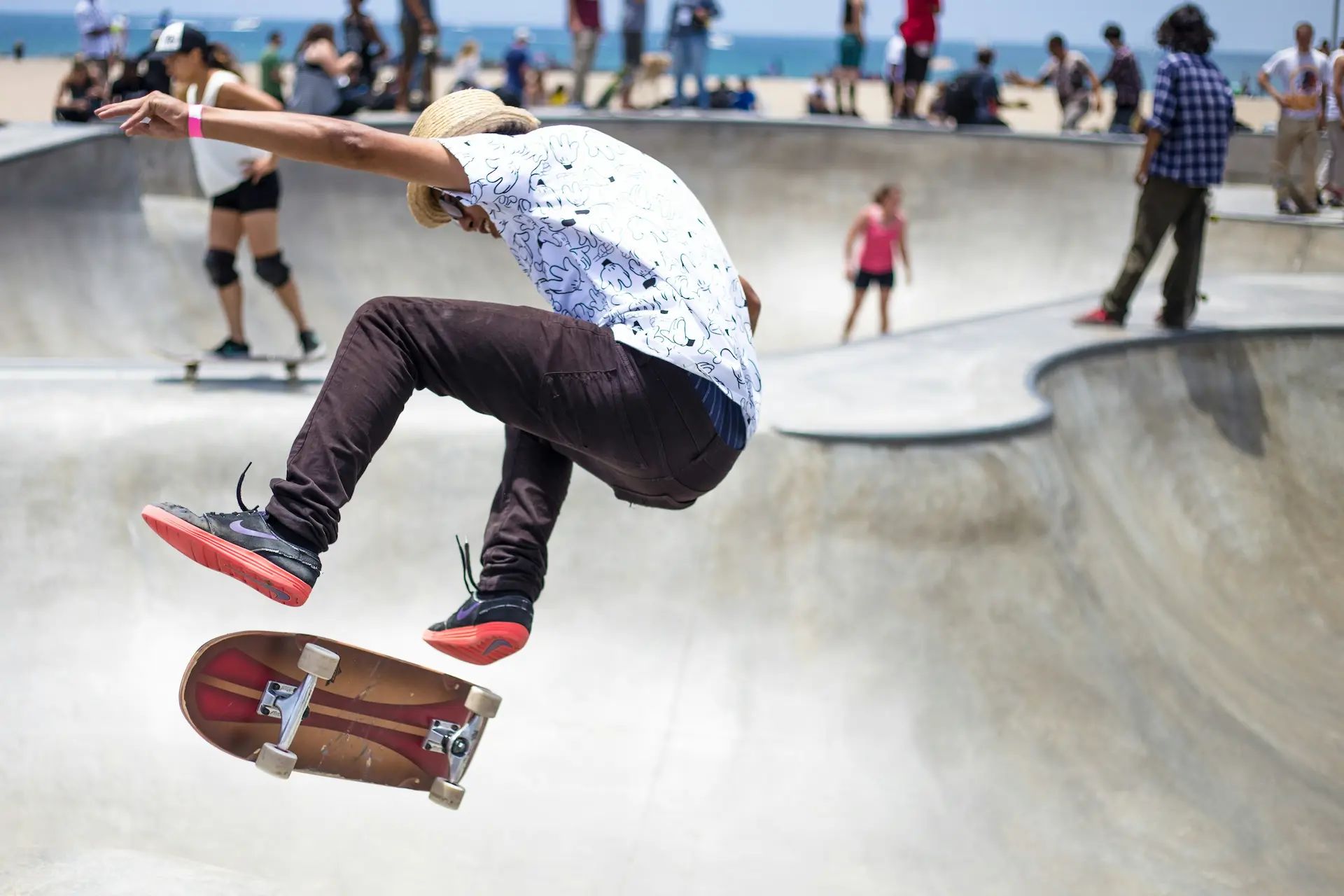 Photo of a guy doing an ollie at a skate park with a crowd of people in the background.