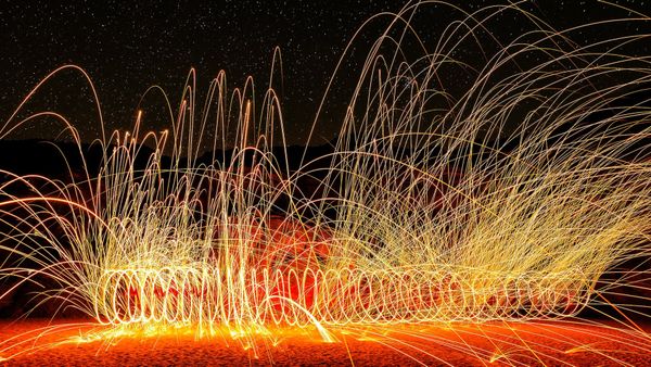 Long exposure photo of a fire poi player. It's dark, there are a lot of traces left by sparks.