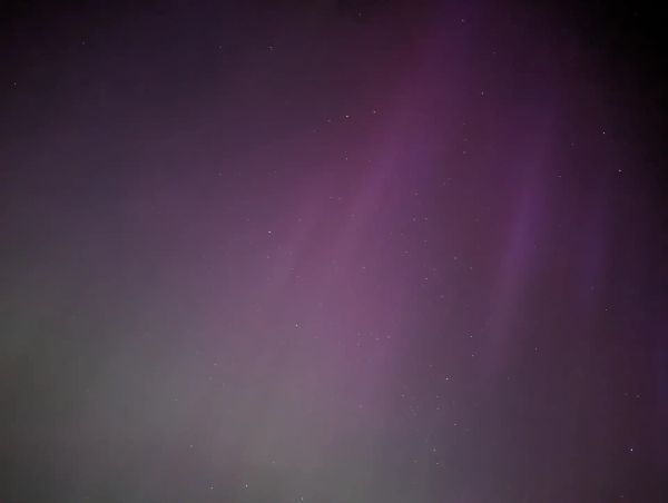Faint green and purple Northern Light streaks in the night sky.