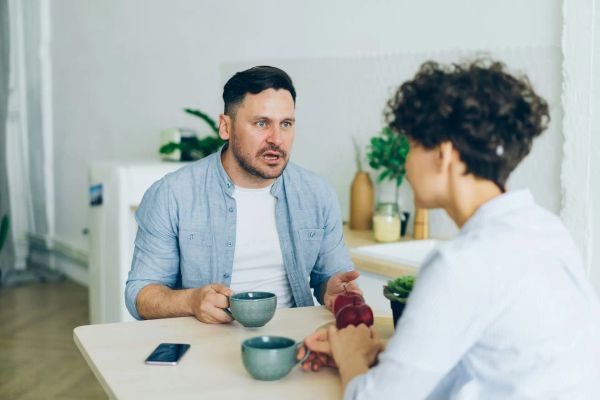 Couple at a table, guy is angry at woman.