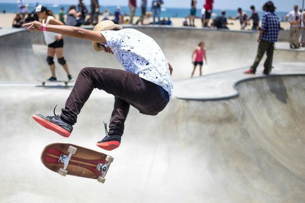Photo of a guy doing an ollie at a skate park with a crowd of people in the background.