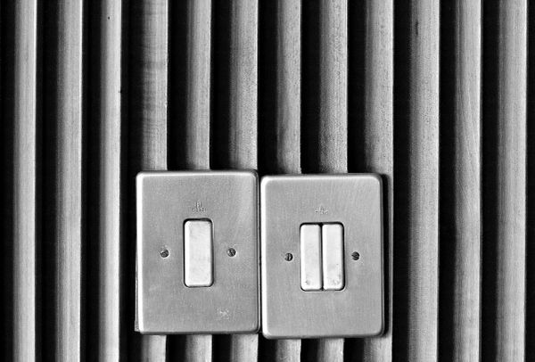 Two light switches on textured wooden wall. One is a double switch.
