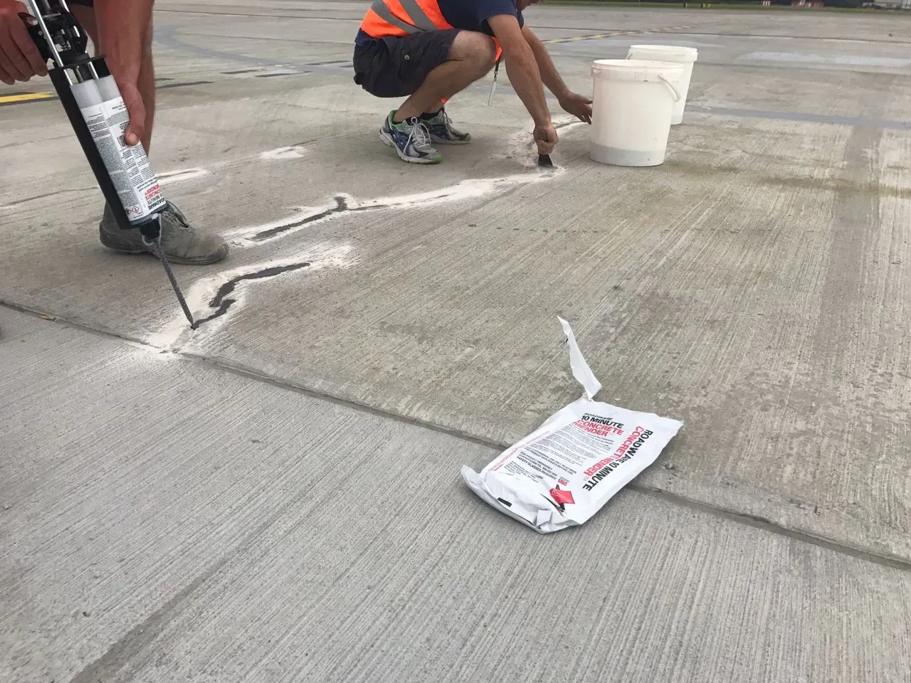 Two men repairing concrete cracks
