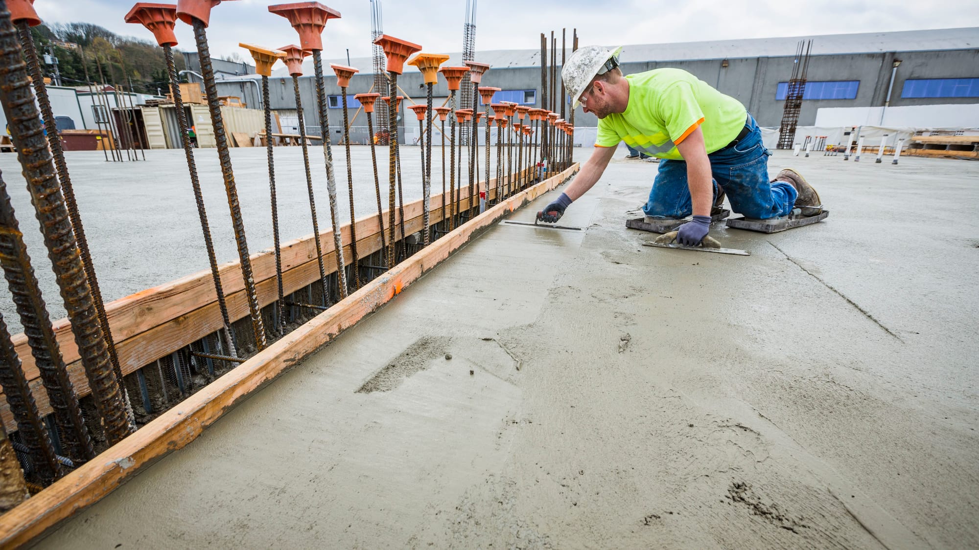 Man wearing a hard hat and high visibility shirt finishing the concrete slab