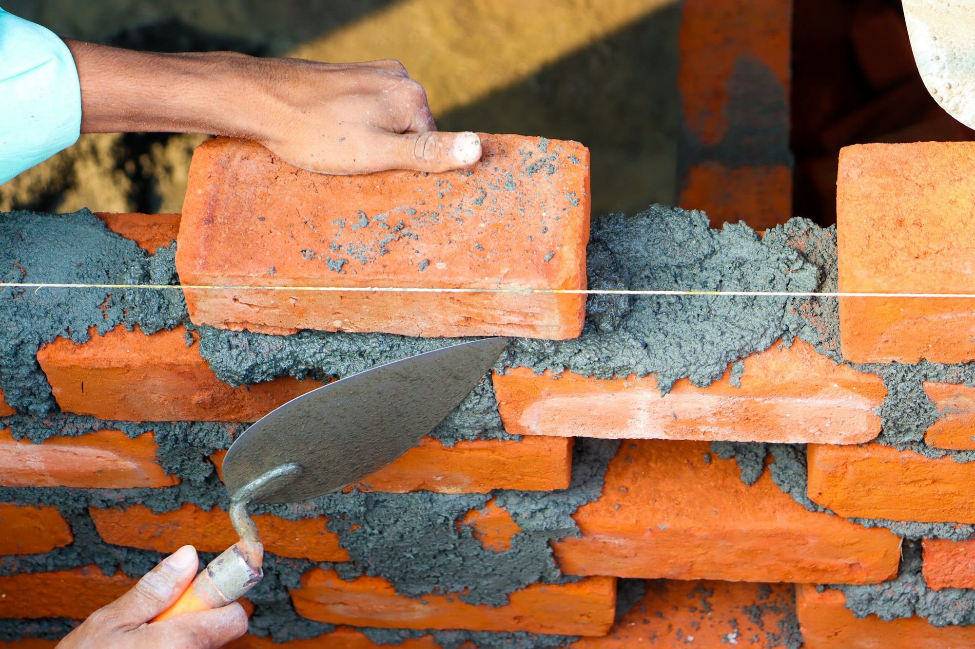 a brick wall being built with a pair of hands