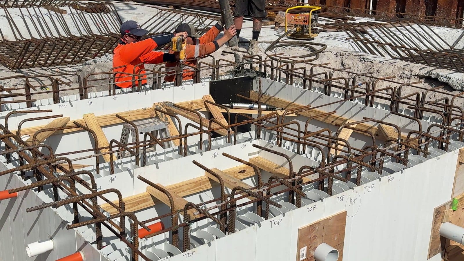 The boom pump placing concrete into the tank walls, with the crew working along the top