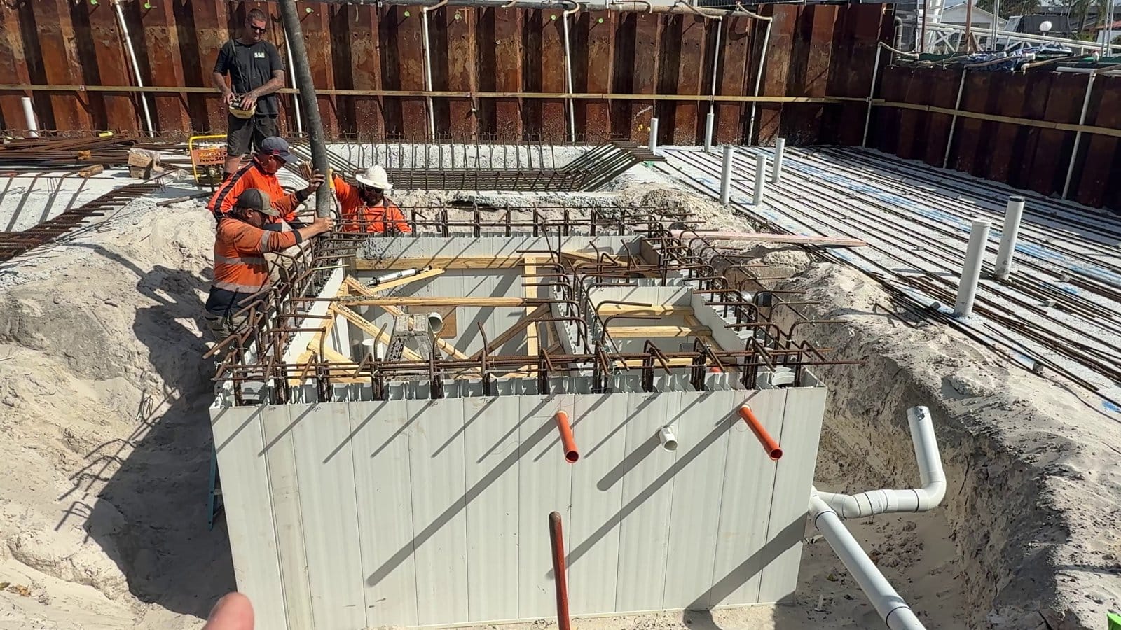 Core filling a tank wall while a second worker runs the vibrator between the bars