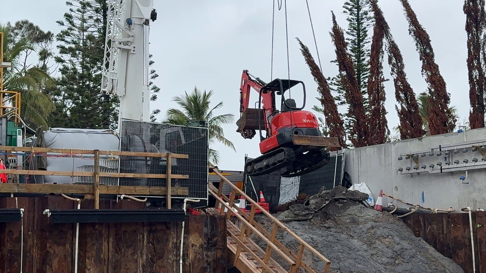 A 3 tonne excavator being lowered into the basement by the 70 tonne crane