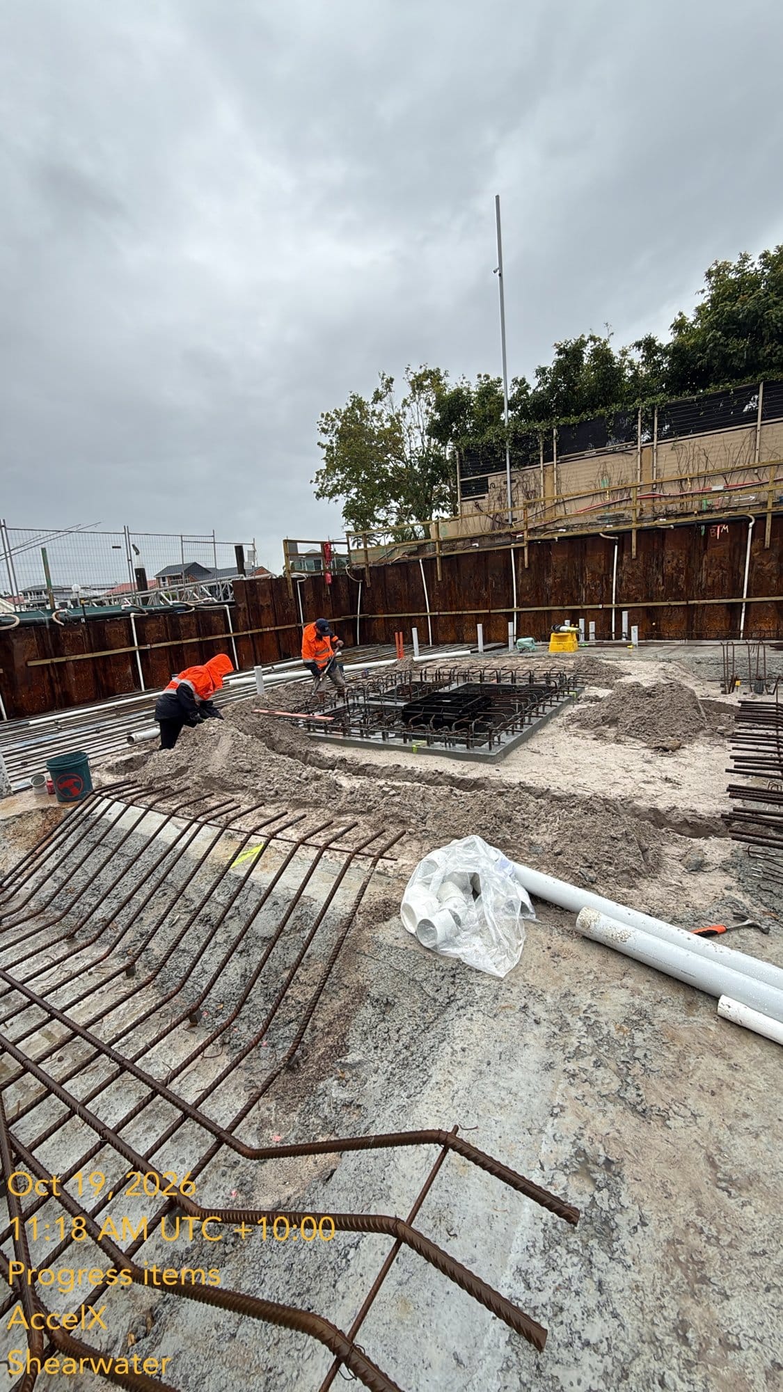 The crew shovelling sand back in around the sewer tank, with the slab steel starter bars in the foreground