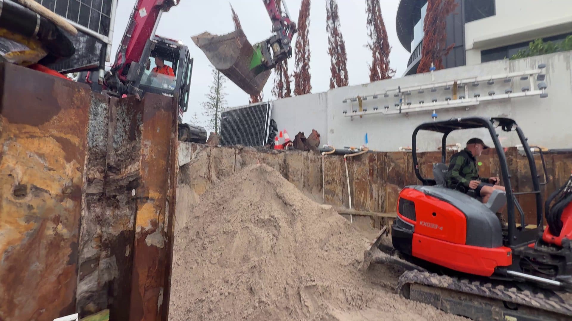 The little 3 tonne excavator pulling sand back inside the basement