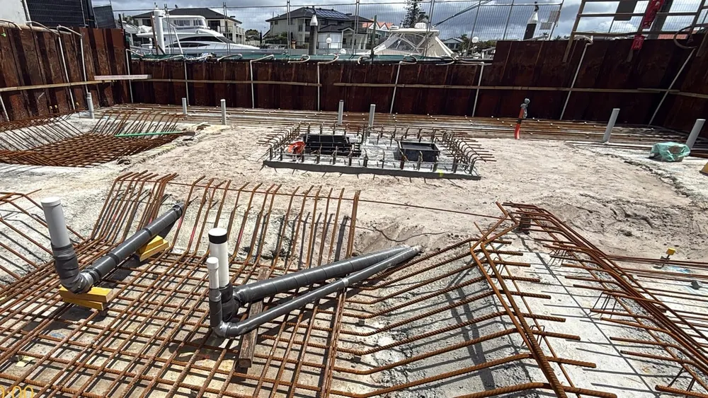 The backfilled sewer and stormwater tanks with wrapped pipes rising through the basement slab steel