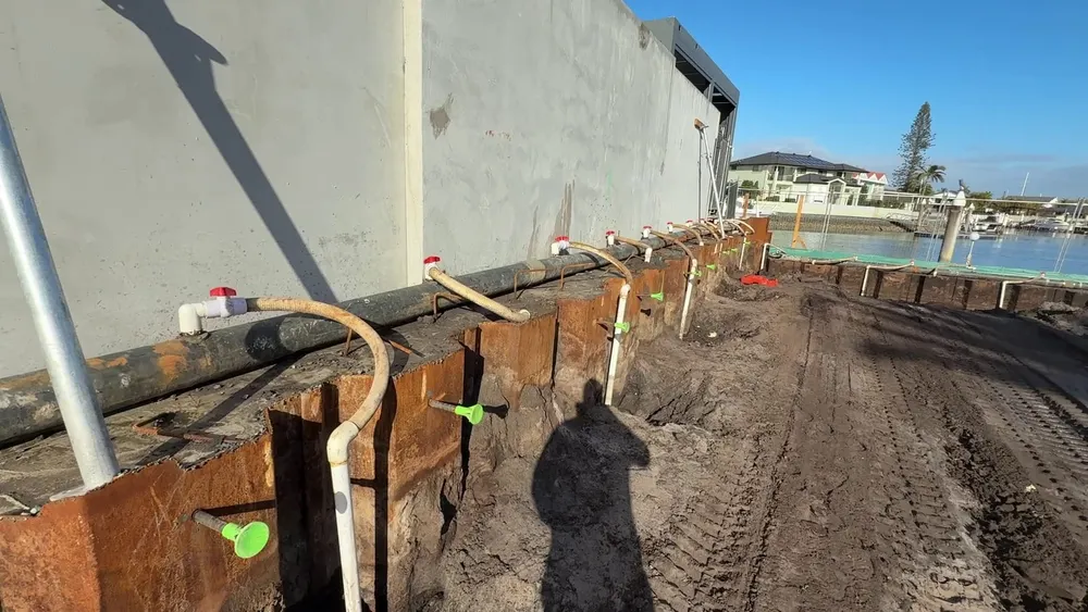 Dewatering header main pipe along the sheet piling, with a valve and flexible hose connecting each spear riser