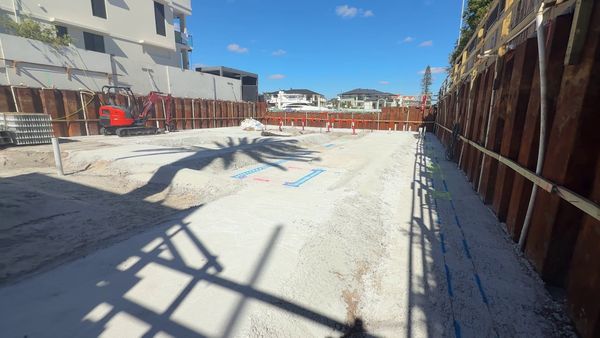 The finished blinding slab inside the steel sheet piling, with blue set-out lines for the basement walls and grids