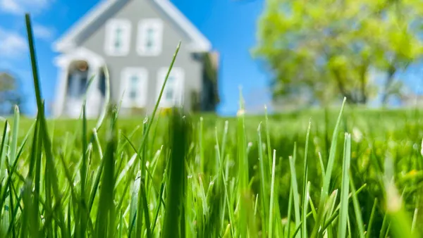 Green grass and a house and tree shown