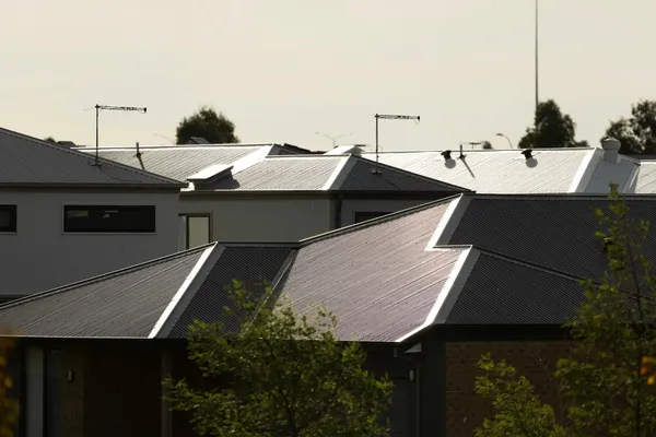 Corrugated metal roofs on suburban houses under a pale sky