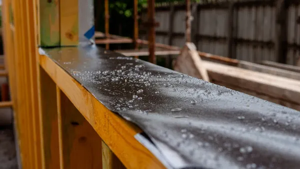 Raindrops on a black waterproof membrane covering a wooden wall frame