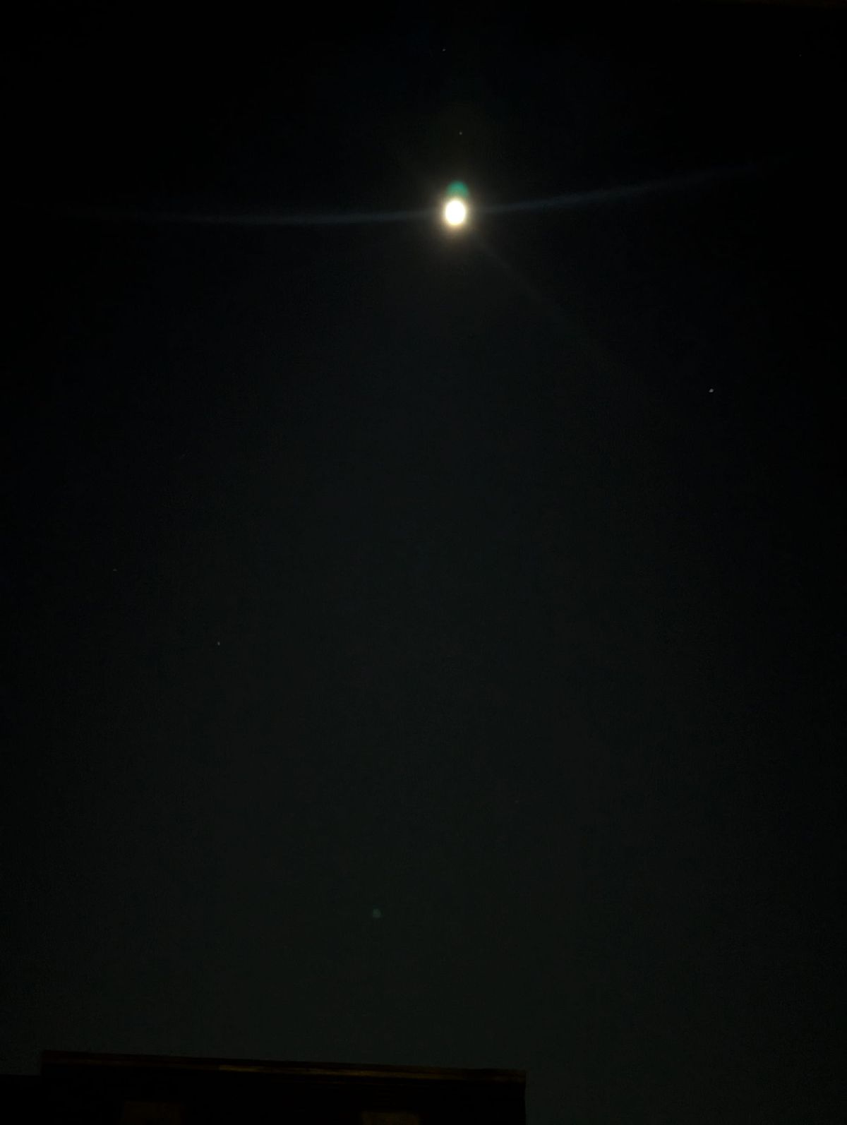 Blurry white-ish full moon against black sky. 