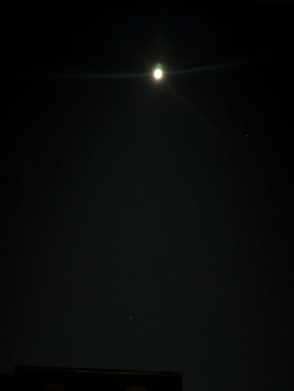 Blurry white-ish full moon against black sky. 