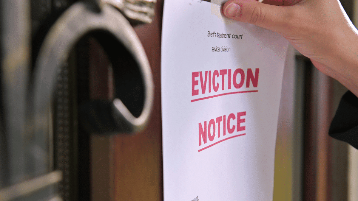 A hand placing an eviction notice placed on the door