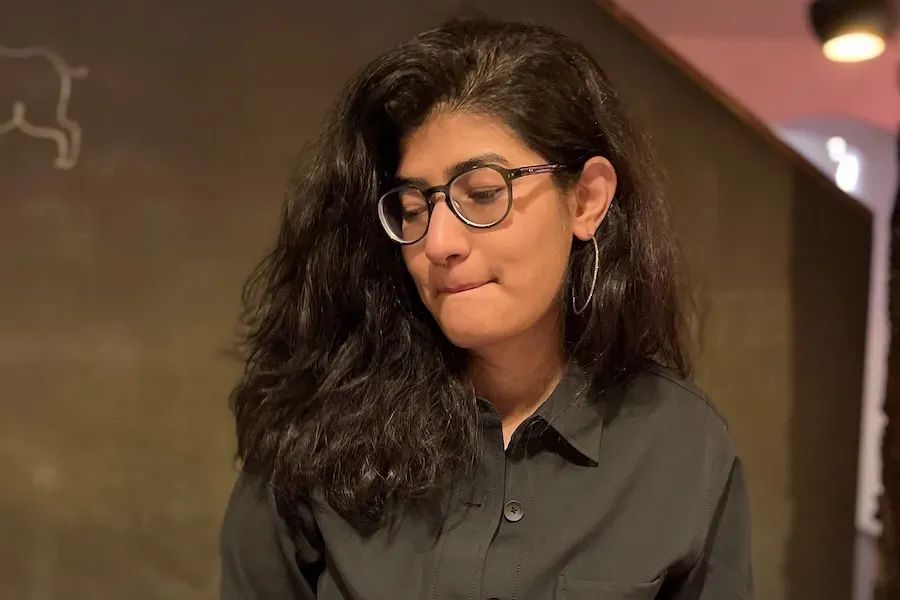 A picture of Shivani in a green shirt-jacket getting ready to devour a plate of food.
