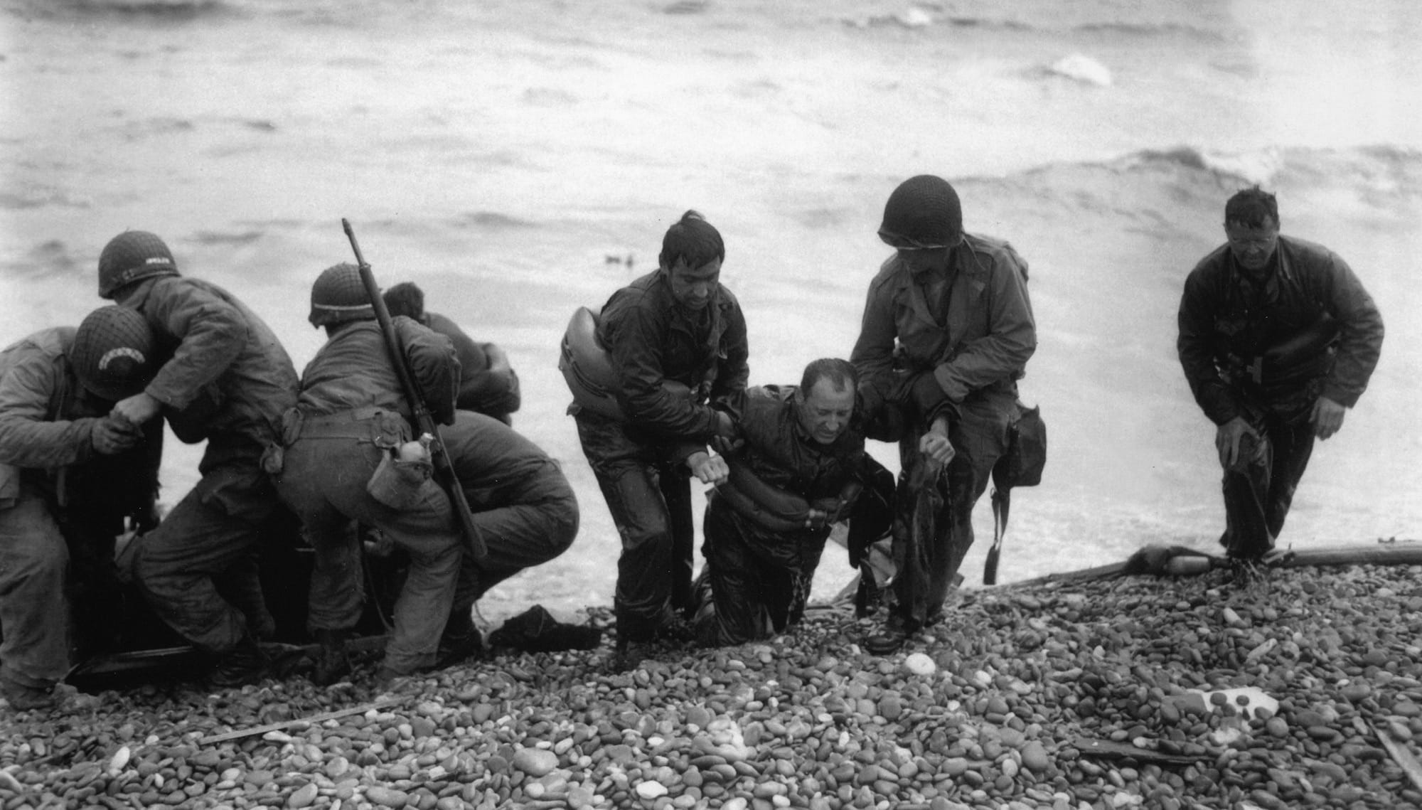 Soldiers helping a wounded comrade on a beach
