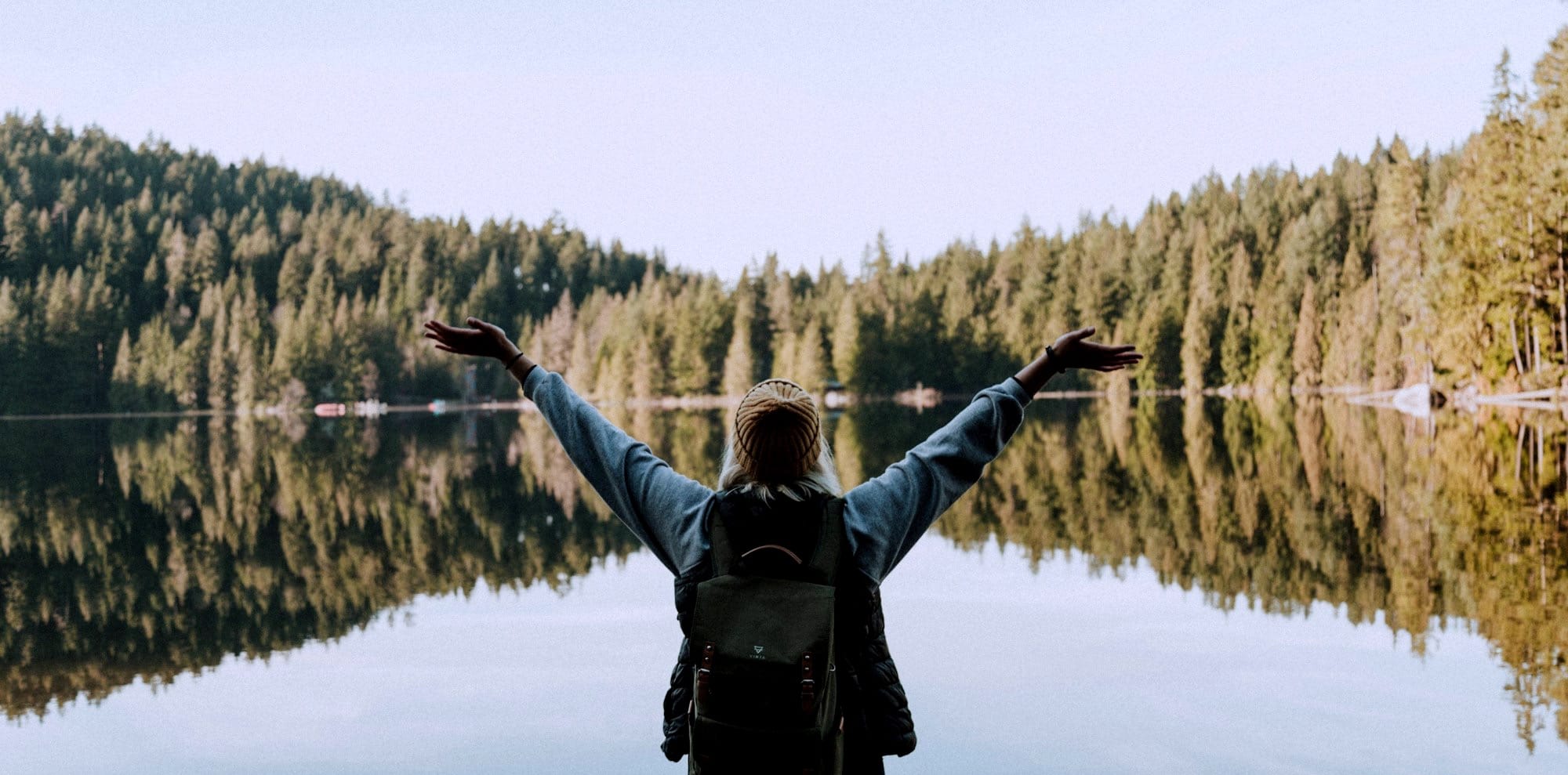 woman open her arms facing calm body of water