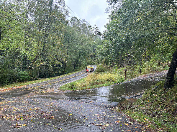 fire truck parked in the middle of a road, blocked by downed trees and power lines
