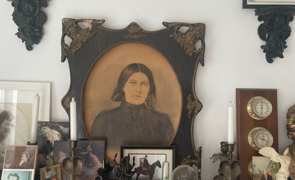 A sepia photograph in a decorative dark wooden and metal frame showing a serious woman in black. 