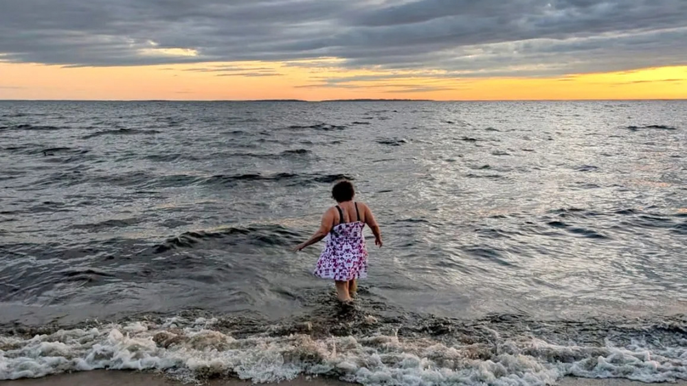 Kim Kitchen walking into the sunset waves of Lake Nipissing, by Liz Lott