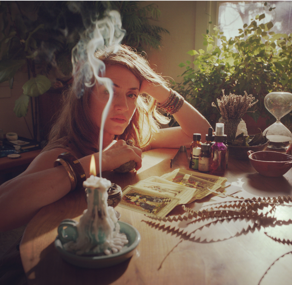 Amanda sits with a candle, face slightly obscured by incense smoke