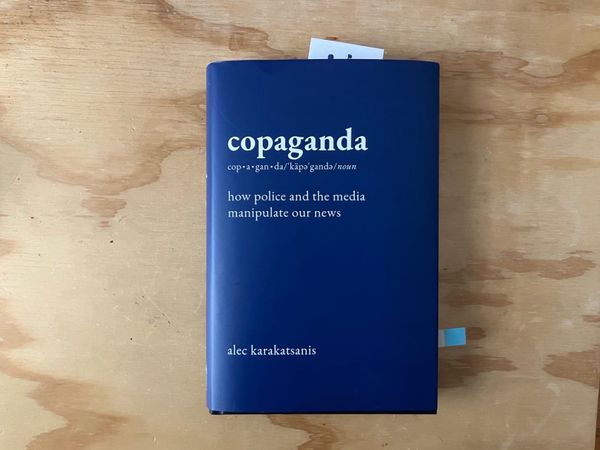 photo of a blue book on plywood background - "copaganda" by alec karakatsanis