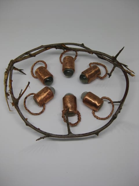Six cat's eye talismans by Die Booth arranged in a circle and surrounded by thorny vines
